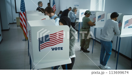 Arabic woman in hijab votes in booth in polling station office 113699674