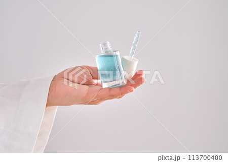 Blue serum with pipette in a womans hands in a robe. Blue serum with pipette in a womans hands in a robe. 113700400