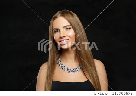 Charming woman with makeup wearing jewelry necklace with sapphire and diamond on black background 113700678