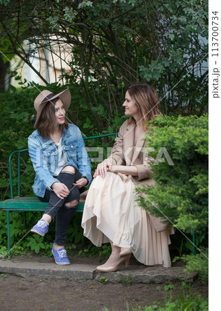 Nice friends talking and sitting on a park bench outdoors 113700734