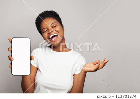 Cheerful woman showing smartphone with empty blank screen display. Model in white t-shirt with phone 113701274