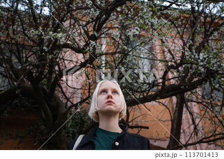 Teenager in spring against blossom tree flowers background 113701413