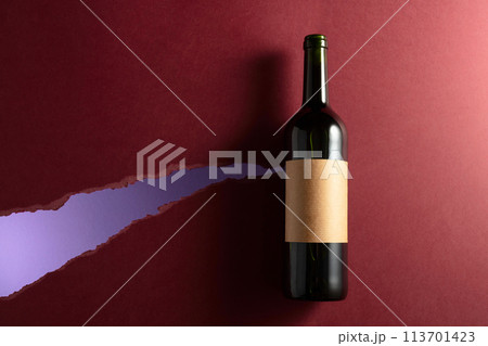 Bottle of red wine with old empty label on a dark red background. Bottle of red wine with old empty label on a dark red background. 113701423