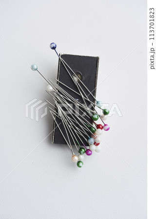Multicolored pins on a white background. Pins and a sewing magnet. Multicolored pins on a white background. Pins and a sewing magnet. 113701823