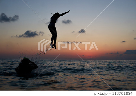 Happy family on sea beach. Happy vacation and holidays concept. Young girl jumping in the sea Happy family on sea beach. Happy vacation and holidays concept. Young girl jumping in the sea 113701854