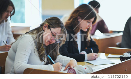 Children's education. Funny schoolchildren and their positive female teacher play fun games in creative lesson. Elementary school students laugh loudly and clap their hands together in classroom. 113702150