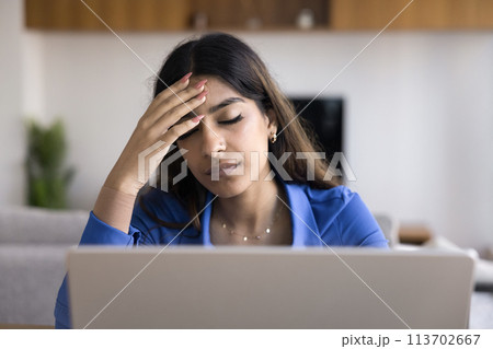 Exhausted young Indian freelancer woman with closed eyes at laptop 113702667