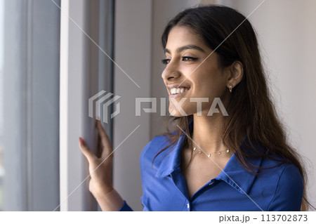 Happy dreamy beautiful 20s Indian girl looking at window away Happy dreamy beautiful 20s Indian girl looking at window away 113702873