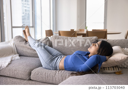 Calm relaxed young Indian woman resting on soft comfortable couch 113703040