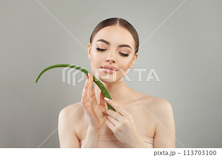 Beautiful woman with green aloe vera leaf. Female model with healthy clean fresh skin portrait. Beautiful woman with green aloe vera leaf. Female model with healthy clean fresh skin portrait. 113703100