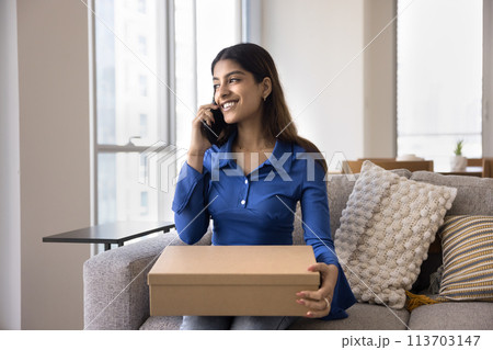 Cheerful satisfied young Indian consumer woman holding paper cardboard box 113703147