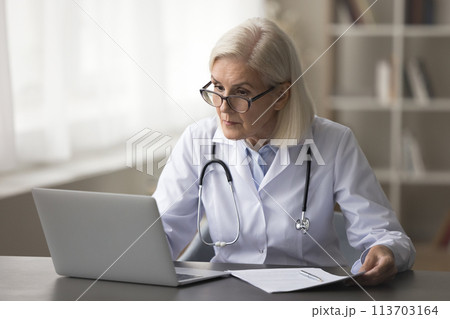 Serious mature woman therapist or cardiologist working on laptop Serious mature woman therapist or cardiologist working on laptop 113703164