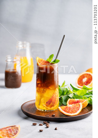 Coffee with orange juice (bumble) in a tall glass with ice and mint on a wooden plate  113703201