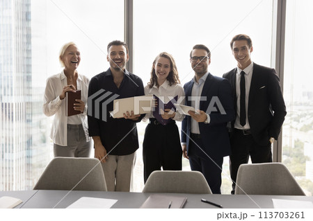 Teammates standing in row gathered in modern conference room 113703261