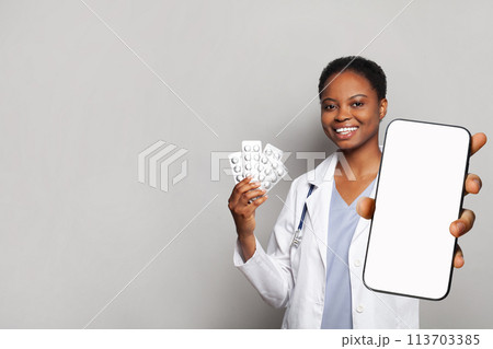 Positive doctor shows a phone with a blank display and pills. Online medical consultation  113703385