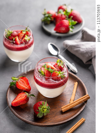 Strawberry and cream panna cotta in glasses with fresh berries on a wooden plate  113703693