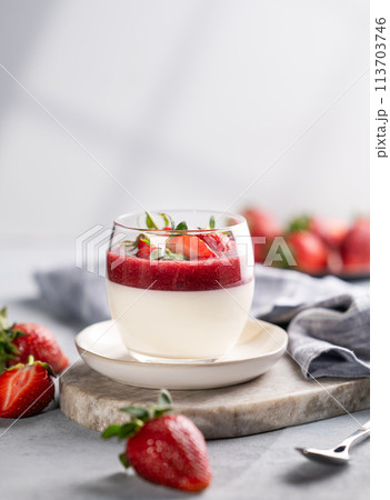 Panna cotta with strawberry and cream in glass with fresh berries on a marble board  113703746