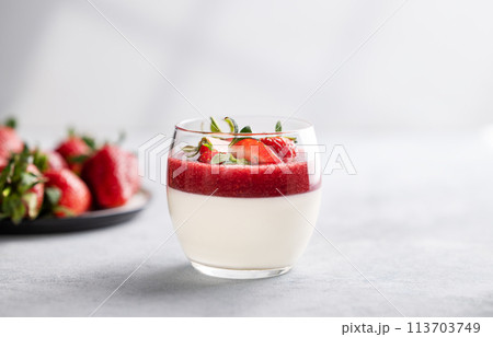 Panna cotta with strawberry and cream in glass with fresh berries on a light background  113703749