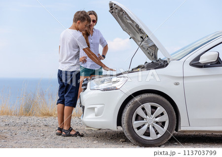 Young woman with her son standing at broken down car having trouble with vehicle 113703799