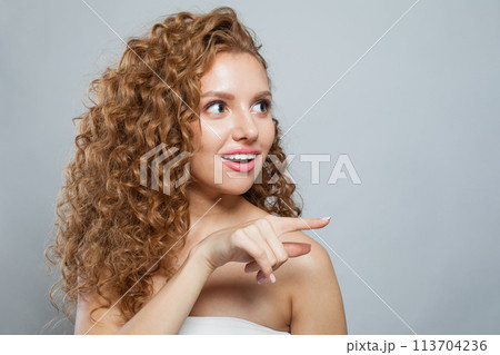 Shocked woman pointing finger. Beautiful female model with natural make-up, frizzy long hair Shocked woman pointing finger. Beautiful female model with natural make-up, frizzy long hair 113704236