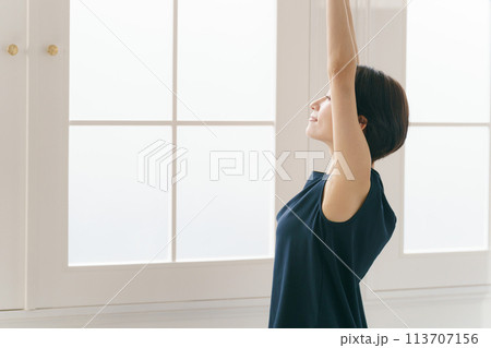 窓際でストレッチをする30代女性 113707156