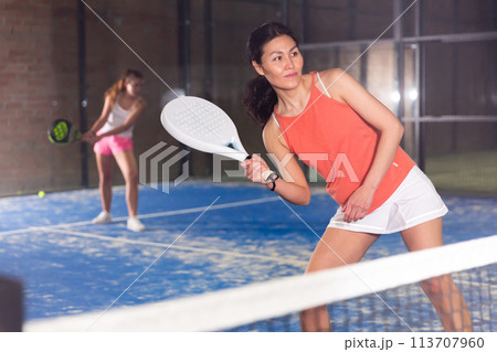 Concentrated asian woman playing paddle tennis indoors 113707960