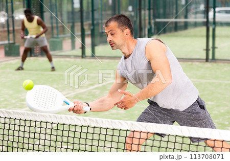Young adult men playing doubles paddle tennis 113708071