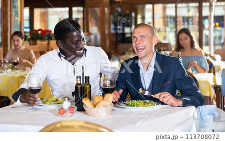 Friends enjoying dinner with wine at restaurant 113708072