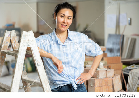 Portrait of satisfied asian woman against the backdrop of renovated room in cottage 113708218