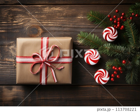 Christmas gift box with red ribbon and candy canes on wooden background 113708221