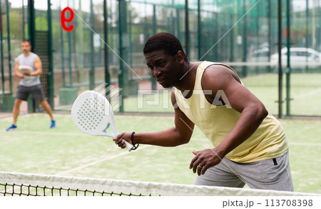 Young adult men playing doubles paddle tennis Young adult men playing doubles paddle tennis 113708398
