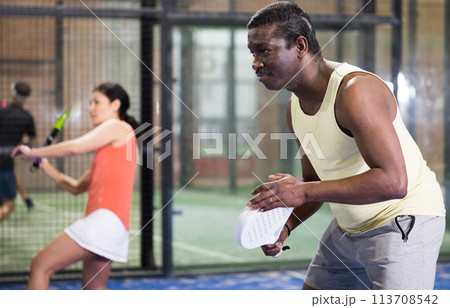 African american man playing paddle tennis on padel court 113708542