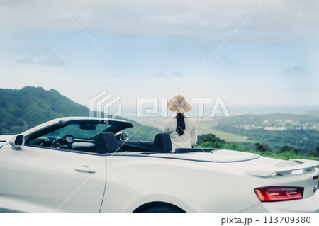 見晴らしのいい丘に停めたオープンカー海に乗り込む女性 見晴らしのいい丘に停めたオープンカー海に乗り込む女性 113709380