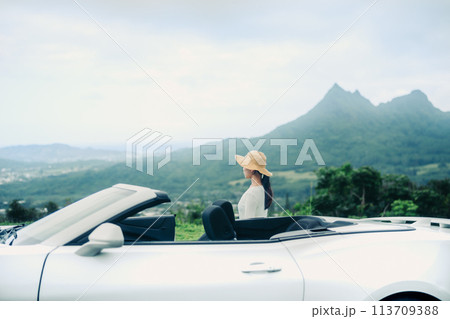 見晴らしのいい丘に停めたオープンカー海に乗り込む女性 113709388