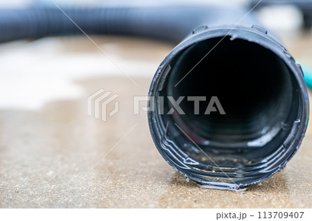 Selective focus on the front opening of a residential sump pump discharging water from the end of a flexible black hose Selective focus on the front opening of a residential sump pump discharging water from the end of a flexible black hose 113709407