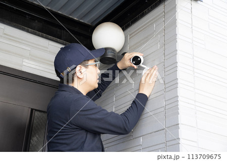 壁に防犯カメラを取り付ける男性作業員 113709675