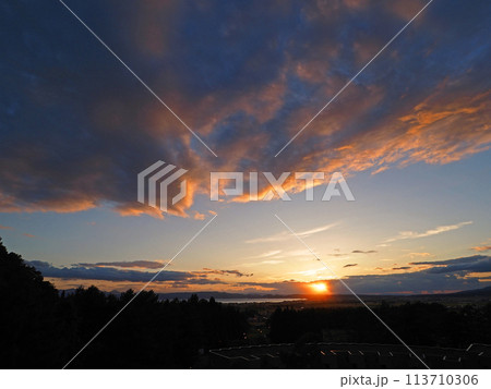 猪苗代湖湖畔に沈む夕日、オレンジ色に輝く雲が青空に印象的で綺麗だ。 猪苗代湖湖畔に沈む夕日、オレンジ色に輝く雲が青空に印象的で綺麗だ。 113710306