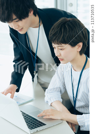 オフイスでパソコン操作をする若い男女 オフイスでパソコン操作をする若い男女 113710535