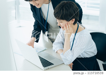 オフイスでパソコン操作をする若い男女 オフイスでパソコン操作をする若い男女 113710539
