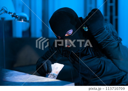Thief counting money dollars during a burglary 113710709