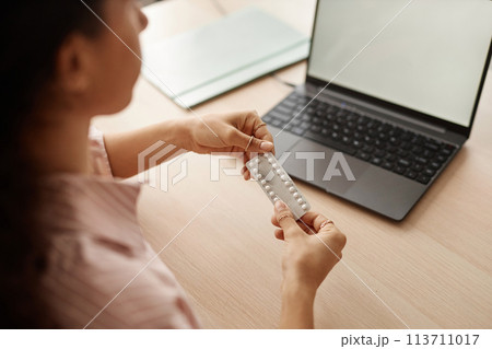Close up of unrecognizable young woman holding blister of birth control pills and researching female health questions online copy space Close up of unrecognizable young woman holding blister of birth control pills and researching female health questions online copy space 113711017