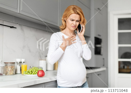 Pregnant woman with discomfort on phone, calling doctor Pregnant woman with discomfort on phone, calling doctor 113711048
