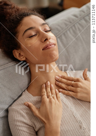 Vertical closeup of young Middle Eastern woman enjoying face and neck massage and self care day Vertical closeup of young Middle Eastern woman enjoying face and neck massage and self care day 113711146