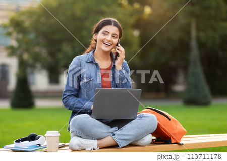 Content student on phone with laptop at campus 113711178