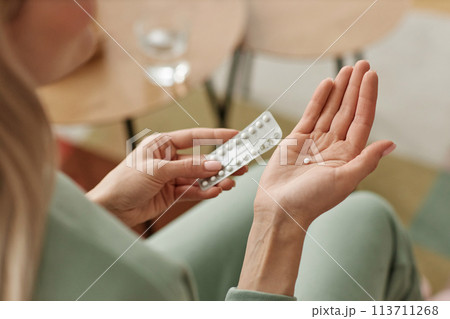 Close up of unrecognizable woman taking birth control pill at home in open hand copy space 113711268