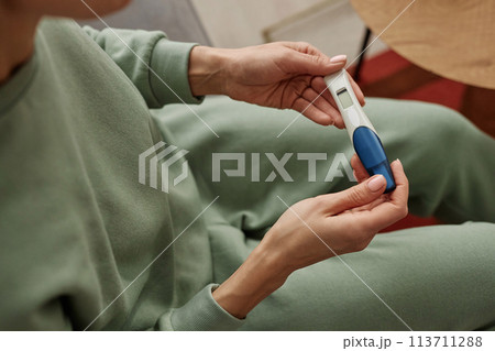 High angle close up of unrecognizable young woman holding pregnancy test with blank screen copy space High angle close up of unrecognizable young woman holding pregnancy test with blank screen copy space 113711288