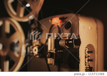 Retro projector playing motion picture. dark room. Timeless flicker of old films 113711368