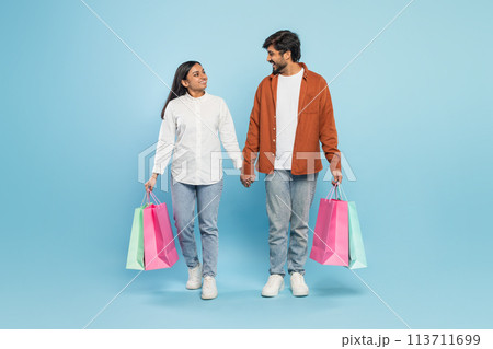 Couple walking with shopping bags looking at each other 113711699