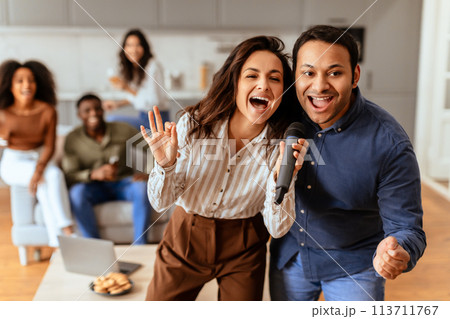 Couple singing enthusiastically into a mic at home Couple singing enthusiastically into a mic at home 113711767