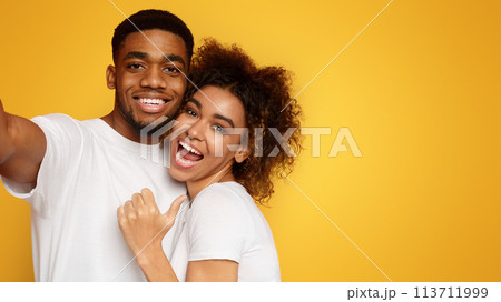 Positive african american couple hugging and taking selfie Positive african american couple hugging and taking selfie 113711999